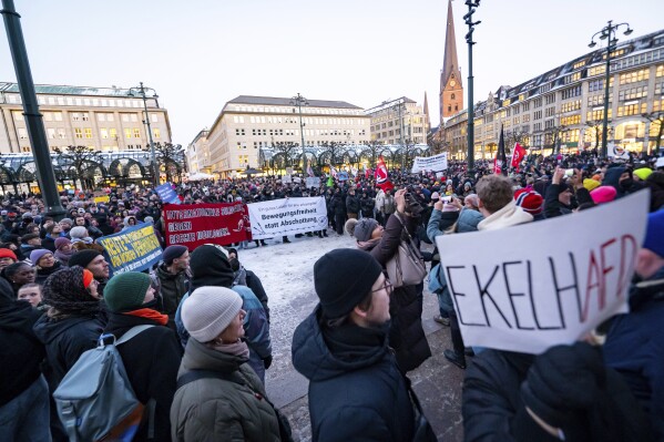 Demonstrators stand with banners and placards as they protest against the right-wing extremist activities in the Rathausmarkt in Hamburg, Germany, Friday Jan. 19, 2024. (Jonas Walzberg/dpa via AP)