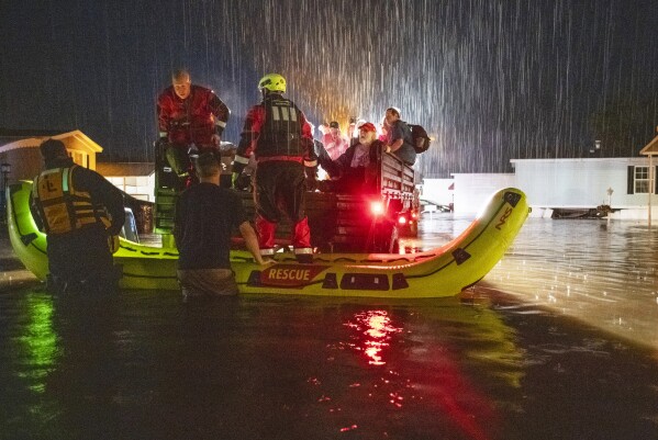Firefighters use boats and a military truck to evacuate residents and pets as floodwaters rise in the Meadowbrook Acres neighborhood of Leominster, Mass., Monday, Sept. 11, 2023. (Rick Cinclair/Worcester Telegram & Gazette via AP)
