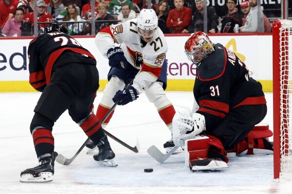 Florida Panthers' Eetu Luostarinen (27) looses control of the puck skating between Carolina Hurricanes' Sean Walker (26) and goaltender Frederik Andersen (31) during the first period of Game 2 of the NHL hockey Stanley Cup Eastern Conference finals in Raleigh, N.C., Thursday, May 22, 2025. (AP Photo/Karl DeBlaker)