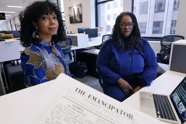 Amber Payne, left, and Deborah Douglas co-editors-in-chief of the new online publication of "The Emancipator" pose at their office inside the Boston Globe, Wednesday, Feb. 2, 2022, in Boston. Boston University's Center for Antiracist Research and The Boston Globe's Opinion team are collaborating to resurrect and reimagine The Emancipator, the first abolitionist newspaper in the United States, which was founded more than 200 years ago. The new incarnation of The Emancipator will explore ways to reframe the national conversation around racial injustice. (AP Photo/Charles Krupa)