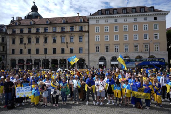 People attend a presentation of an installation ahead of the Group E match between Romania and Ukraine at the Euro 2024 soccer tournament in Munich, Germany, Monday, June 17, 2024. A poignant installation has been unveiled ahead of Ukraine’s first match at the European Championship. A destroyed stand from Kharkiv’s Sonyachny stadium that was built for Euro 2012 has been displayed in a square in Munich ahead of the team’s opener against Romania. (AP Photo/Ariel Schalit)