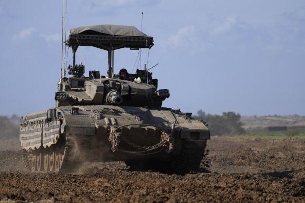 An Israeli tank drives through farm land in as it returns from the Gaza Strip, in southern Israel, near the Gaza border, Thursday, Feb. 1, 2024. (AP Photo/Tsafrir Abayov)