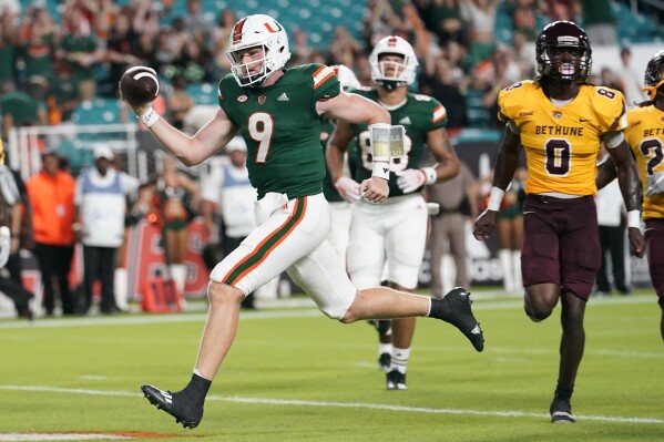 Miami quarterback Tyler Van Dyke (9) runs to score a touchdown past Bethune-Cookman cornerback Iverson Clement (0) during the first half of an NCAA college football game Thursday, Sept. 14, 2023, in Miami Gardens, Fla. (AP Photo/Lynne Sladky)