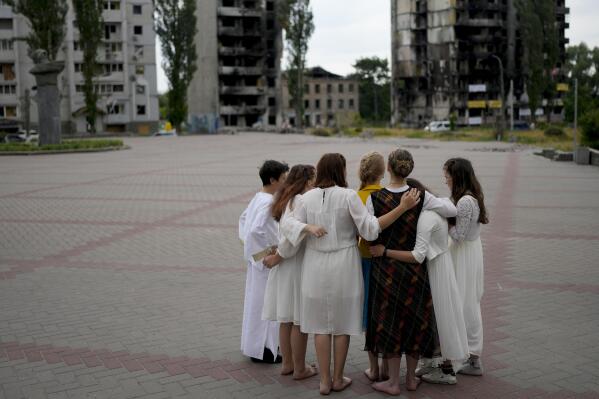 Young people gather in a circle as they rehearse for a performance near a building bombed in Russian attacks in Borodyanka, on the outskirts of Kyiv, Ukraine, Tuesday, June 21, 2022. (AP Photo/Natacha Pisarenko)