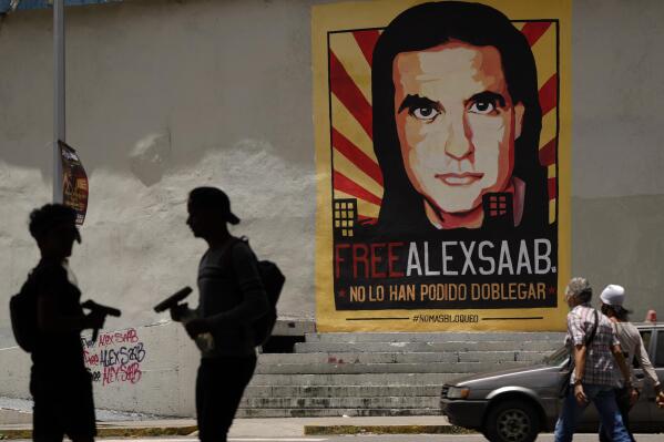 FILE - In this Sept. 9, 2021 file photo, pedestrians walk near a poster asking for the freedom of Colombian businessman and Venezuelan special envoy Alex Saab, and that reads in Spanish "They haven't been able to bend him," in Caracas, Venezuela. Venezuela’s government quietly offered in 2020 to release imprisoned Americans, the so-called Citgo 6 along with two former Green Berets tied to a failed cross border raid, in exchange for the U.S. letting go Saab, a key financier of President Nicolás Maduro, who was extradited to Miami in Oct. 2021. (AP Photo/Ariana Cubillos, File)