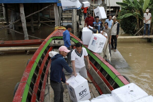 Electoral workers unload ballot boxes from a boat during the distribution of election paraphernalia to remote villages, in Pemulutan, South Sumatra, Indonesia, Tuesday, Feb. 13, 2024. Indonesia, the world's third-largest democracy, will open its polls on Wednesday, Feb. 14, to nearly 205 million eligible voters in presidential and legislative elections, the fifth since Southeast Asia's largest economy began democratic reforms in 1998. (AP Photo/Muhammad Hatta)