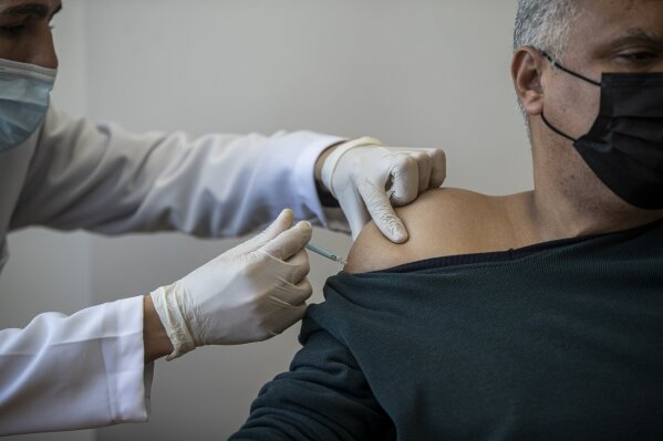 A Palestinian man receives a shot of the Russian-made Sputnik V coronavirus vaccine, at an UNRWA clinic in Gaza City, Wednesday, March 17, 2021. The Palestinian Authority says it will receive 62,000 coronavirus vaccine doses through a World Health Organization partnership designed to help poor countries.(AP Photo/Khalil Hamra)