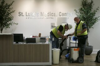 In this April 23, 2020, photo, contract workers join the Army Corps of Engineers as they get the currently dormant St. Luke's Hospital ready for reopening for the possible surge of coronavirus patients in Phoenix. As states gear up to reopen, a poll finds a potential obstacle to controlling coronavirus: nearly 1 in 10 adults say cost would keep them from seeking help if they thought they were infected. The Gallup-West Health Healthcare Costs Survey out Tuesday, April 28, finds that 9% of those age 18 and over would avoid seeking treatment because of concerns about the cost of care, even if they thought they were infected with the coronavirus.  (AP Photo/Ross D. Franklin)
