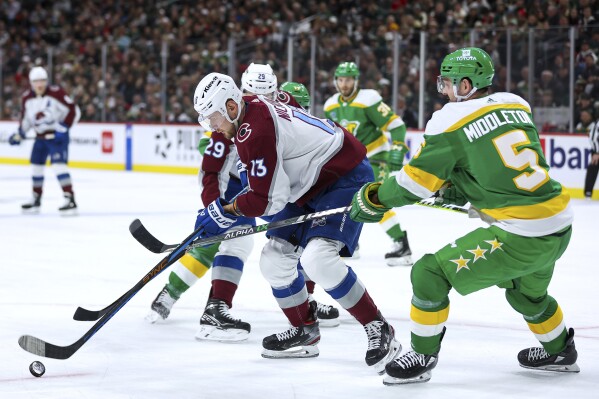 Colorado Avalanche right wing Valeri Nichushkin (13) skates with the puck next to Minnesota Wild defenseman Jake Middleton (5) during the second period of an NHL hockey game Friday, Nov. 24, 2023, in St. Paul, Minn. (AP Photo/Matt Krohn)