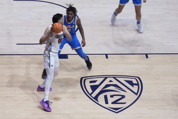 FILE - A Pac-12 logo is shown on the floor of Haas Pavilion as California forward Fardaws Aimaq (00) looks to pass while being defended by UCLA guard Brandon Williams during an NCAA college basketball game in Berkeley, Calif., Feb. 10, 2024. The University of California Board of Regents is expected to accept a recommendation that UCLA pay University of California at Berkeley $10 million a year for six years as a result of the Bruins’ upcoming move to the Big Ten and the demise of the Pac-12. (AP Photo/Jeff Chiu, File)