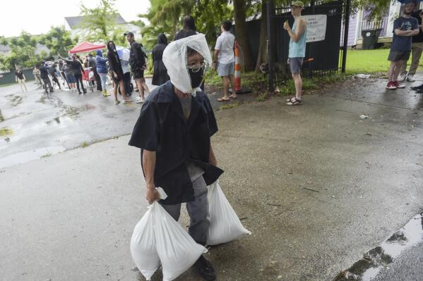 A resident takes home sandbags from a city run sandbag distribution location at the Dryades YMCA along Oretha Castle Haley Blvd., Friday, Aug. 27, 2021, in New Orleans, as residents prepare for Hurricane Ida.  (Max Becherer/The Times-Picayune/The New Orleans Advocate via AP)