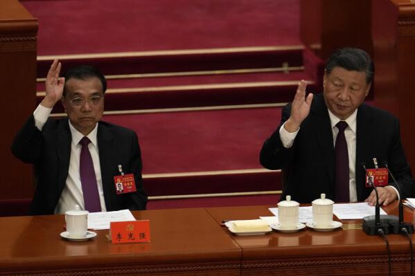 Chinese President Xi Jinping looks over as Chinese Premier Li Keqiang raises his hand to vote at the closing ceremony of the 20th National Congress of China's ruling Communist Party at the Great Hall of the People in Beijing, Saturday, Oct. 22, 2022. Chinese Premier Li Keqiang, the nation's No. 2 official and a chief proponent of economic reforms, is among four of the seven members of the nation's all-powerful Politburo Standing Committee who will not be reappointed in a leadership shuffle Sunday. (AP Photo/Ng Han Guan)