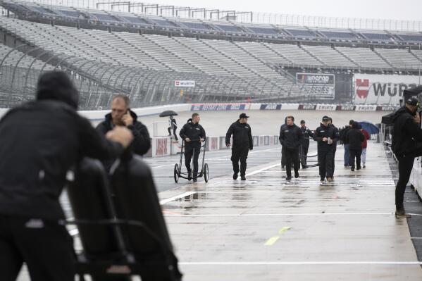 Team members walk down pit road after the NASCAR 400 auto race was postponed due to weather at Dover Motor Speedway Sunday, April 30, 2023, in Dover, Del. (AP Photo/Jason Minto)