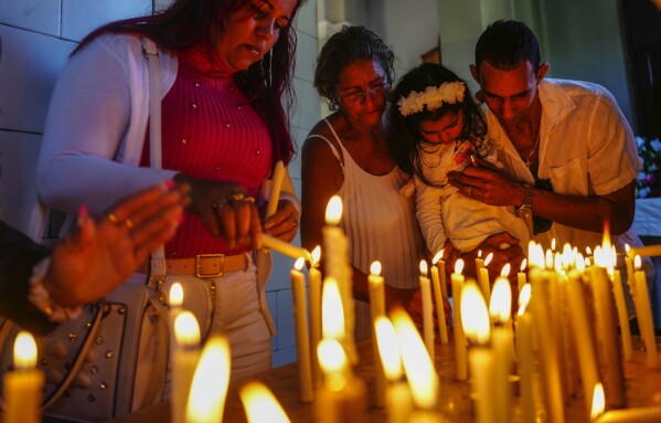 FILE - People light candles in honor of Cuba's patron saint, the Virgin of Charity of Cobre, at her shrine in El Cobre, Cuba, Feb. 11, 2024. The Vatican-recognized Virgin, venerated by Catholics and followers of Afro-Cuban Santeria traditions, is at the heart of Cuban identity. (AP Photo/Ramon Espinosa, File)