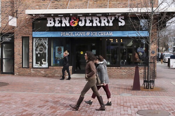 FILE - Pedestrians walk on Church St., past the Ben & Jerry's shop, in Burlington, Vt., Wednesday, March 11, 2020. Unilever, the company that makes Ben & Jerry’s ice cream, Dove soaps and Vaseline, said Tuesday, March 19, 2024, that it is cutting 7,500 jobs and spinning off its ice cream business to reduce costs and boost profits. (AP Photo/Charles Krupa, File)