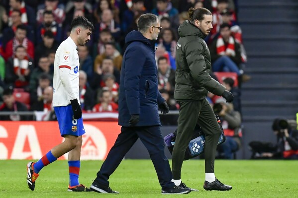 Barcelona's Pedri, left, leaves the field after sustaining an injury during a Spanish La Liga soccer match between Athletic Bilbao and Barcelona at the San Mames stadium in Bilbao, Spain, on Sunday, March 3, 2024. (AP Photo/Alvaro Barrientos)