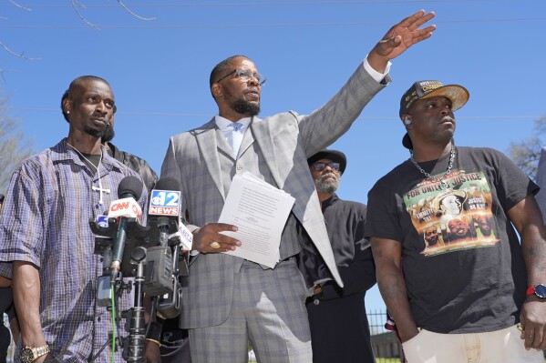 Michael Corey Jenkins, left, and Eddie Terrell Parker, right, stand with lead attorney Malik Shabazz, as they call on a federal judge Monday, March 18, 2024, at a news conference in Jackson, Miss., to impose the harshest possible penalties against six former Mississippi Rankin County law enforcement officers who committed numerous acts of racially motivated, violent torture on them in 2023. The six former law officers pleaded guilty to a number of charges for torturing them. (AP Photo/Rogelio V. Solis)