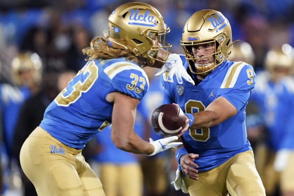 UCLA quarterback Collin Schlee, right, hands the ball off to running back Carson Steele during the first half of an NCAA college football game against Arizona State, Saturday, Nov. 11, 2023, in Pasadena, Calif. (AP Photo/Ryan Sun)