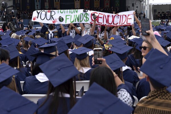 George Washington University students carry a sign during a pro-Palestinian protest as George Washington University President Ellen Granberg speaks at a commencement ceremony in Washington, Sunday, May 19, 2024. (AP Photo/Jose Luis Magana)