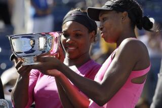 FILE - Serena Williams, left, of the United States, and her sister Venus examine the championship trophy after winning the women's doubles championship over Cara Black, of Zimbabwe, and Liezel Huber, of the United States, at the U.S. Open tennis tournament in New York, Monday, Sept. 14, 2009. Serena and Venus Williams were given a wild-card entry for women's doubles at the U.S. Open on Saturday, Aug. 27, 2022, making it their first tournament as a team in more than four years. (AP Photo/Darron Cummings, File)