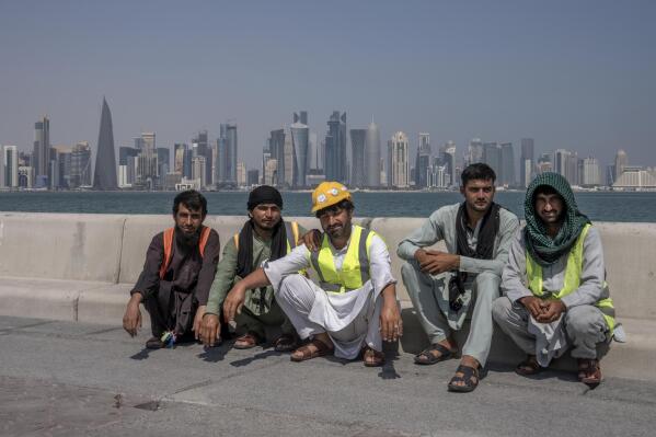 FILE - Pakistani migrant laborers pose for a photograph, as they take a break, on the corniche, overlooking the skyline of Doha, Qatar, Wednesday, Oct. 19, 2022. Migrant laborers who built Qatar's World Cup stadiums often worked long hours under harsh conditions and were subjected to discrimination, wage theft and other abuses as their employers evaded accountability, a rights group said in a report released Thursday. (AP Photo/Nariman El-Mofty, File)