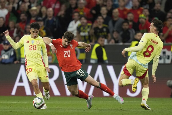 Spain's Pedri, left, and Spain's Fabian Ruiz, right, challenge Portugal's Pedro Neto during the Nations League final soccer match between Portugal and Spain at the Allianz Arena in Munich, Germany, Sunday, June 8, 2025. (AP Photo/Matthias Schrader)