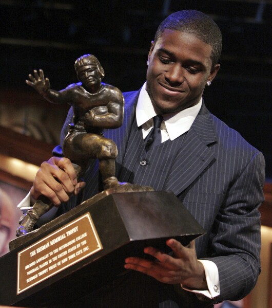 FILE - Southern California tailback Reggie Bush picks up the Heisman Trophy after being announced as the winner of the award in New York, Dec. 10, 2005. Reggie Bush has been reinstated as the 2005 Heisman Trophy winner, Wednesday, April 24, 2024, more than a decade after Southern California returned the award following an NCAA investigation that found he received what were impermissible benefits during his time with the Trojans.(AP Photo/Julie Jacobson, File)