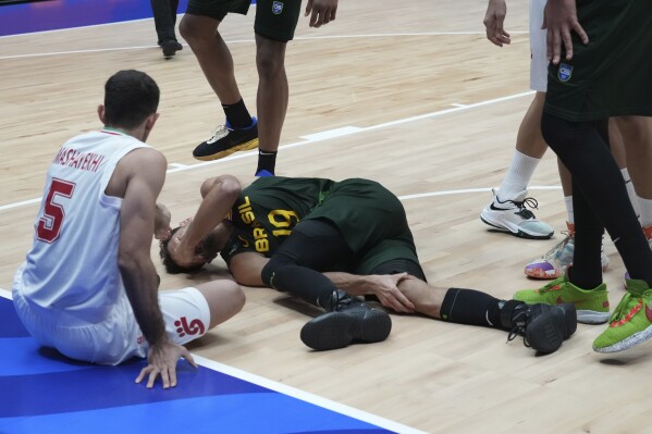 CAPTION CORRECTION: CORRECTS MONTH: Brazil guard Raul Neto Togni (19) lies on the court after an apparent injury during the Basketball World Cup group G match between Iran and Brazil at the Indonesia Arena stadium in Jakarta, Indonesia Saturday, Aug. 26, 2023. (AP Photo/Achmad Ibrahim)