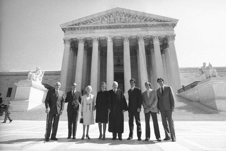 FILE - Justice Sandra Day O'Connor poses for photos on the steps of the Supreme Court before being sworn in with her family on Sept. 26, 1981. From left are: Justice O'Connor's father, Harry Day; her husband, John J. O'Connor; her mother, Ada Mae Day; O'Connor; Chief Justice Warren Burger; and her sons, Brian, Jay and Scott. The late Justice Sandra Day O'Connor, the first woman to serve on the Supreme Court and an unwavering voice of moderate conservatism for more than two decades, will lie in repose in the court's Great Hall on Monday, Dec. 18, 2023. (AP Photo/Bob Daugherty, File)