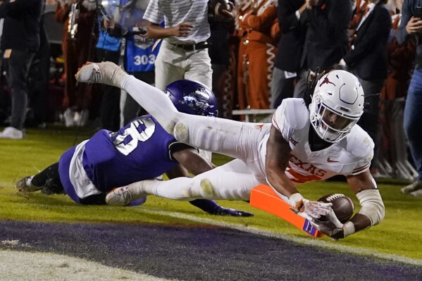 Texas running back Jonathon Brooks, right, dives into the end zone in front of TCU safety Millard Bradford while scoring on a touchdown run during the first half of an NCAA college football game, Saturday, Nov. 11, 2023, in Fort Worth, Texas. (AP Photo/Julio Cortez)