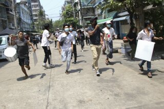 Anti-coup protesters run to avoid military forces during a demonstration in Yangon, Myanmar on Wednesday March 31, 2021. A military and police crackdown on protesters in Myanmar may be driving more people across the border between China and Maynmar, though it is difficult to gauge. (AP Photo)