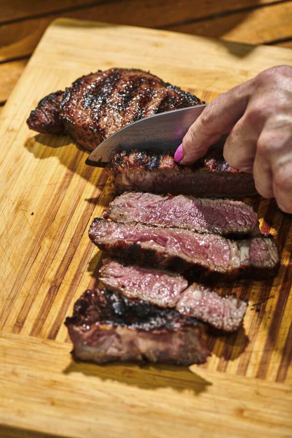 This July 2022, image provided by Cheyenne Cohen shows a grilled steak being sliced in New Milford, Conn. (Cheyenne Cohen via AP)