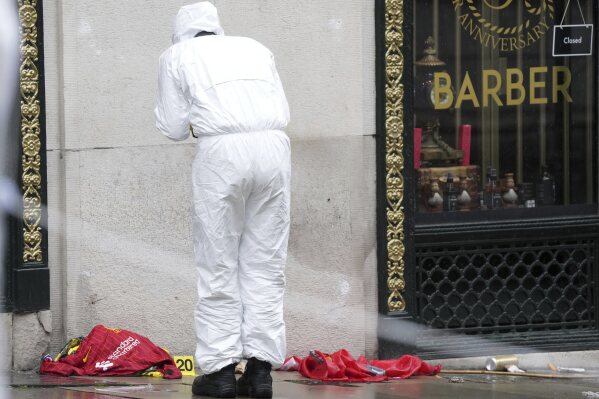 A Forensic officer looks at evidence near the site where a 53-year-old British man plowed a minivan into a crowd of Liverpool soccer fans who were celebrating the city's Premier League championship Monday, injuring more than 45 people in Liverpool, England, Tuesday, May 27, 2025.(AP Photo/Jon Super)