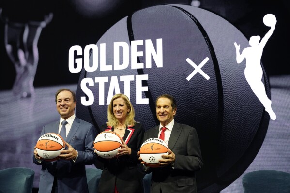 From left, Golden State Warriors CEO Joe Lacob, WNBA Commissioner Cathy Engelbert and Warriors Co-Executive Chairman Peter Guber pose for pictures after an WNBA expansion franchise for the San Francisco Bay Area was announced at Chase Center in San Francisco, Thursday, Oct. 5, 2023. The team will begin play in the 2025 season. (AP Photo/Eric Risberg)
