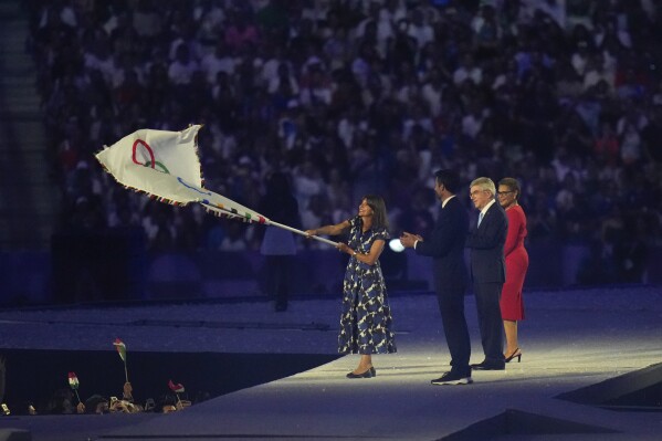 Paris Mayor Anne Hidalgo waves the Olympic flag during the 2024 Summer Olympics closing ceremony at the Stade de France, Sunday, Aug. 11, 2024, in Saint-Denis, France. (AP Photo/Petr David Josek)