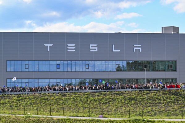 FILE - Demonstrators walk past the Tesla factory in Gruenheide, Germany, May 11, 2024, at the end of their protest. A local council in Germany on Friday May 17, 2024, approved a plan by electric carmaker Tesla to expand the grounds of its first plant in Europe, which has drawn persistent protests this year. (Patrick Pleul/dpa via AP, File)