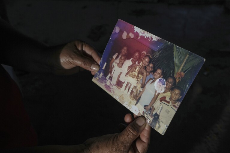 Guadalupe Cobos holds a 20-year-old family photograph, inside her home in El Bosque, in the state of Tabasco, Mexico, Thursday, Nov. 30, 2023. Many residents have left the homes they built in the coastal community, displaced by climate change-driven flooding. Cobos is one of the few still living in El Bosque. (AP Photo/Felix Marquez)