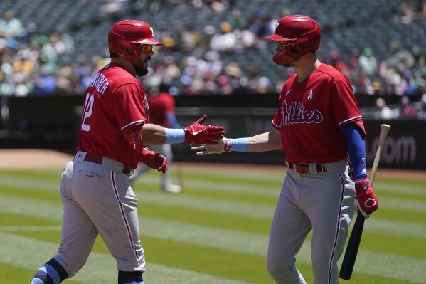 Philadelphia Phillies' Kyle Schwarber, left, is congratulated by Trea Turner after hitting a home run during the first inning of a baseball game against the Oakland Athletics in Oakland, Calif., Sunday, June 18, 2023. (AP Photo/Jeff Chiu)