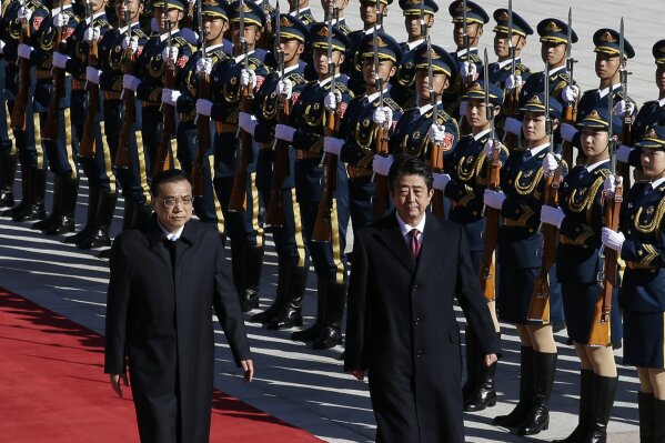 
              Japanese Prime Minister Shinzo Abe, right, and Chinese Premier Li Keqiang review an honor guard during a welcome ceremony at the Great Hall of the People in Beijing, Friday, Oct. 26, 2018. (AP Photo/Andy Wong)
            