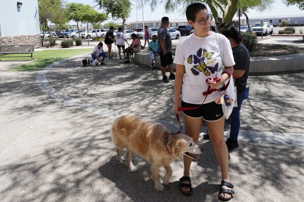 Rori Chang, of Glendale, Ariz., waits in line with her dog Ava to get microchipped at the Maricopa Country Animal Care & Control facility Friday, June 30, 2023, in Phoenix. Most of the U.S. may be looking forward to July Fourth celebrations for dazzling displays of fireworks or setting off firecrackers and poppers with their neighbors. Those with furry, four-legged family members — maybe not so much. They're searching for solutions to the Fourth of July anxiety that fireworks bring. (AP Photo/Ross D. Franklin)