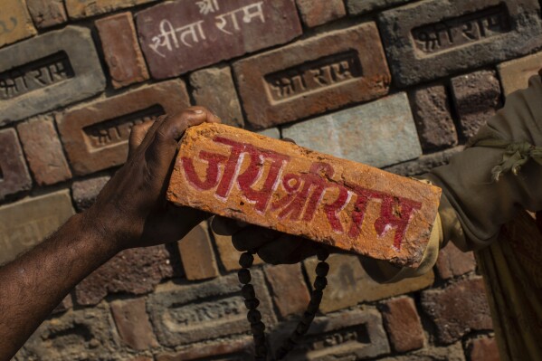 FILE - In this Sunday, Nov. 25, 2018, photo, a man holds a brick reading "Jai Shree Ram" (Victory to Lord Ram) as bricks of the old Babri Mosque are piled up in Ayodhya, in the central Indian state of Uttar Pradesh. Most pre-poll surveys suggest Modi is likely to win the 2024 elections comfortably, especially after he opened a Hindu temple built on the ruins of the historic mosque in northern Ayodhya city in January, which fulfilled his party’s long-held Hindu nationalist pledge. (AP Photo/Bernat Armangue, File)