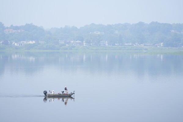 FILE - People fish on the Susquehanna River amidst haze from Canadian wildfires, June 29, 2023, in Harrisburg, Pa. As smoky as the summer has been so far, scientists say it will likely be worse in future years because of climate change. (AP Photo/Matt Rourke, File)