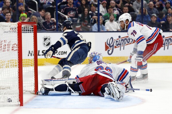 Columbus Blue Jackets forward Jack Roslovic, left, scores past New York Rangers goalie Jonathan Quick, center, and defenseman K'Andre Miller during the second period of an NHL hockey game in Columbus, Ohio, Sunday, Feb. 25, 2024. (AP Photo/Paul Vernon)