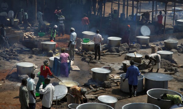 Refugees prepare food including maize porridge donated by USAID and known locally as posho, during the visit of U.N. in Adjumani, Uganda, Aug. 29, 2016. (AP Photo/Stephen Wandera, File)