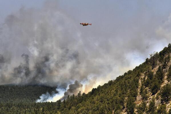 A firefighting plane flies over a plume of smoke near Las Vegas, N.M. on Wednesday, May 4, 2022. The fire has torched 250 square miles (647 square kilometers) over the last several weeks. (AP Photo/Thomas Peipert)