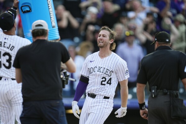 Colorado Rockies' Ryan McMahon arrives at the plate after hitting a grand slam off Tampa Bay Rays pitcher Jason Adam during the ninth inning of a baseball game Friday, April 5, 2024, in Denver. (AP Photo/David Zalubowski)