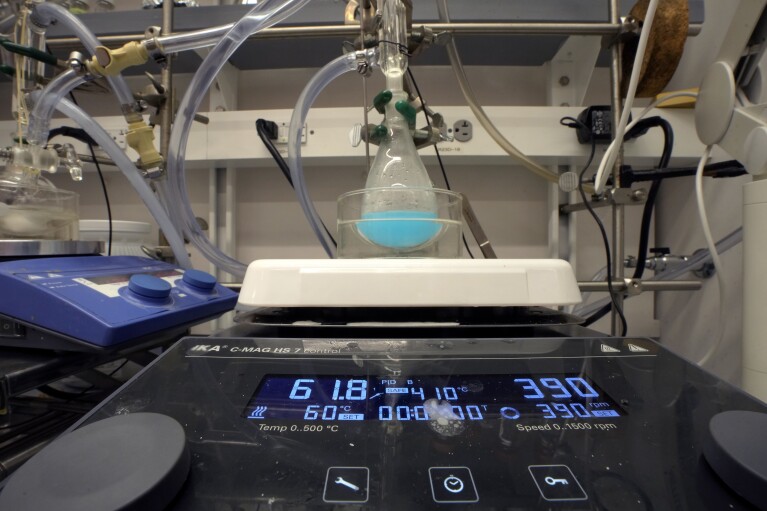 A copper-based candidate for a solid refrigerant is synthesized in a glass flask, center, Thursday, Sept. 14, 2023, in a lab on the campus of Harvard University, in Cambridge, Mass. The process is part of research to develop a more environmentally-friendly solid refrigerant that could be used as an alternative to existing volatile refrigerants. (AP Photo/Steven Senne)