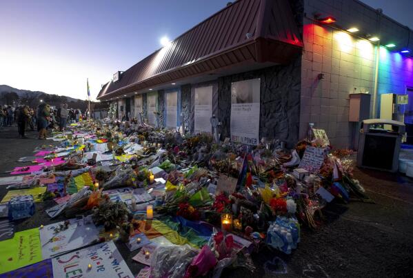 FILE - Mourners gather outside Club Q to visit a memorial, which has been moved from a sidewalk outside of police tape that was surrounding the club, Nov. 25, 2022, in Colorado Spring, Colo. A gunman killed five people at the nightclub last month. (Parker Seibold/The Gazette via AP, File)