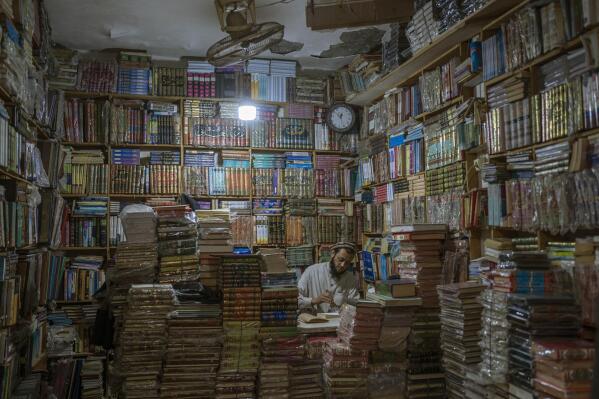 A bookshop owner repairs a book in Herat, Afghanistan, Monday, Nov. 22, 2021. (AP Photo/Petros Giannakouris)