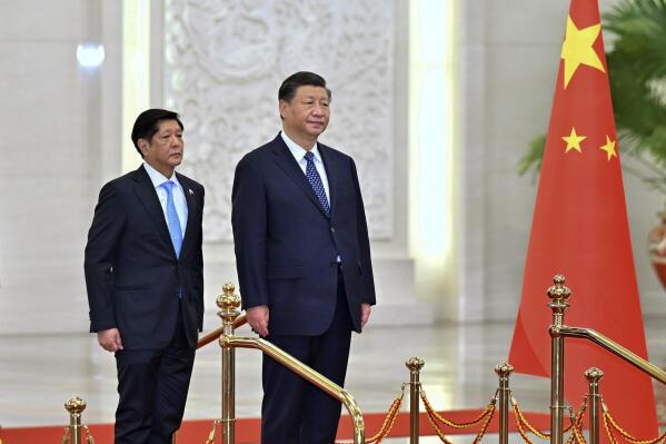 In this photo released by Xinhua News Agency, Visiting Philippine President Ferdinand Marcos Jr., left, and Chinese President Xi Jinping listen to the national anthems of their countries on stage during a welcome ceremony at the Great Hall of the People in Beijing, Wednesday, Jan. 4, 2023. Philippine President Ferdinand Marcos Jr. is pushing for closer economic ties on a visit to China that seeks to sidestep territorial disputes in the South China Sea. (Yue Yuewei/Xinhua via AP)